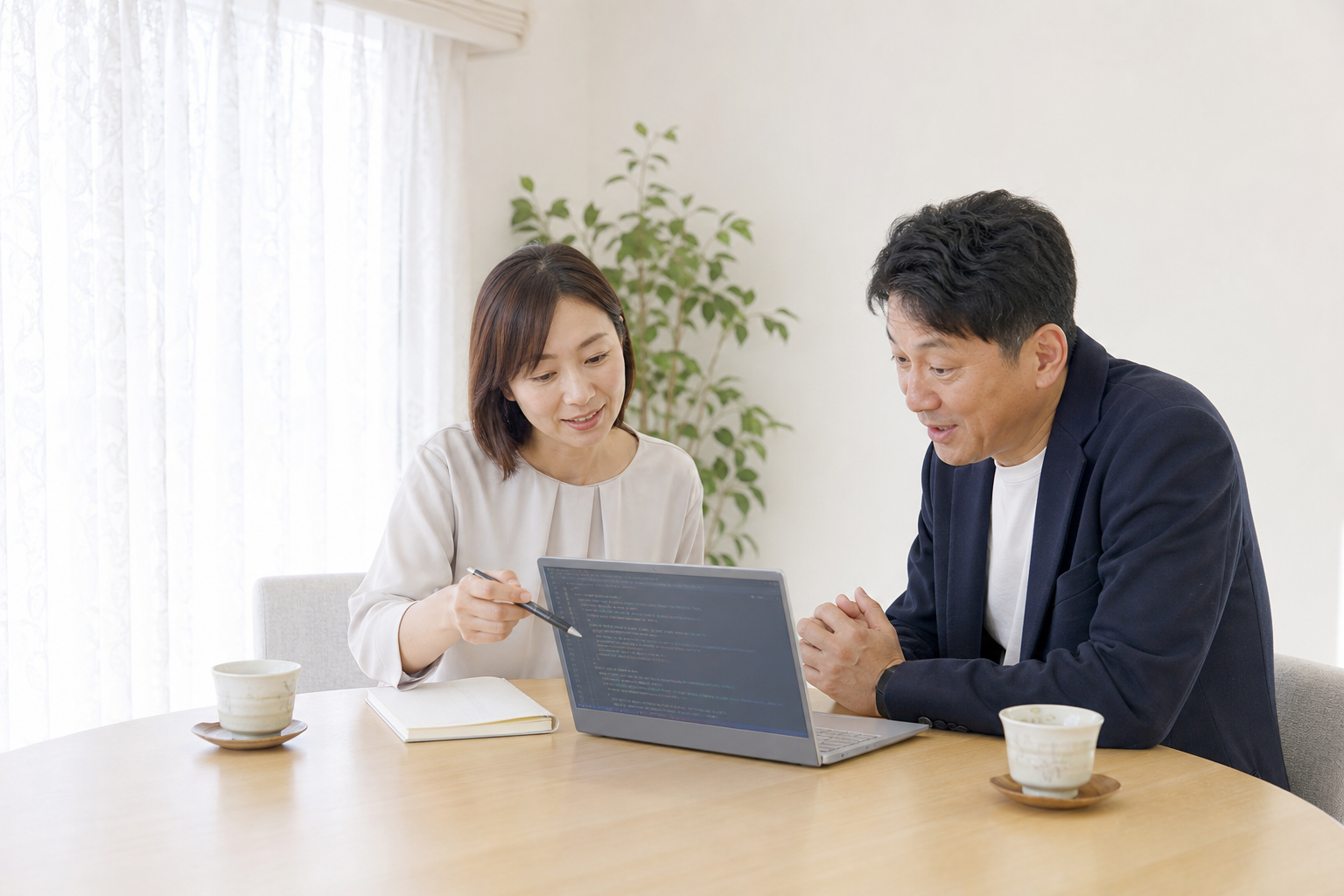 サイト担当者が住宅会社経営者にノートPC画面の構造化データのコードを指しながら説明している対話シーン