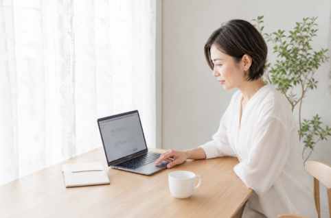 ノートPCの検索窓に「新潟市 工務店」と入力しかけている女性の動作スナップ