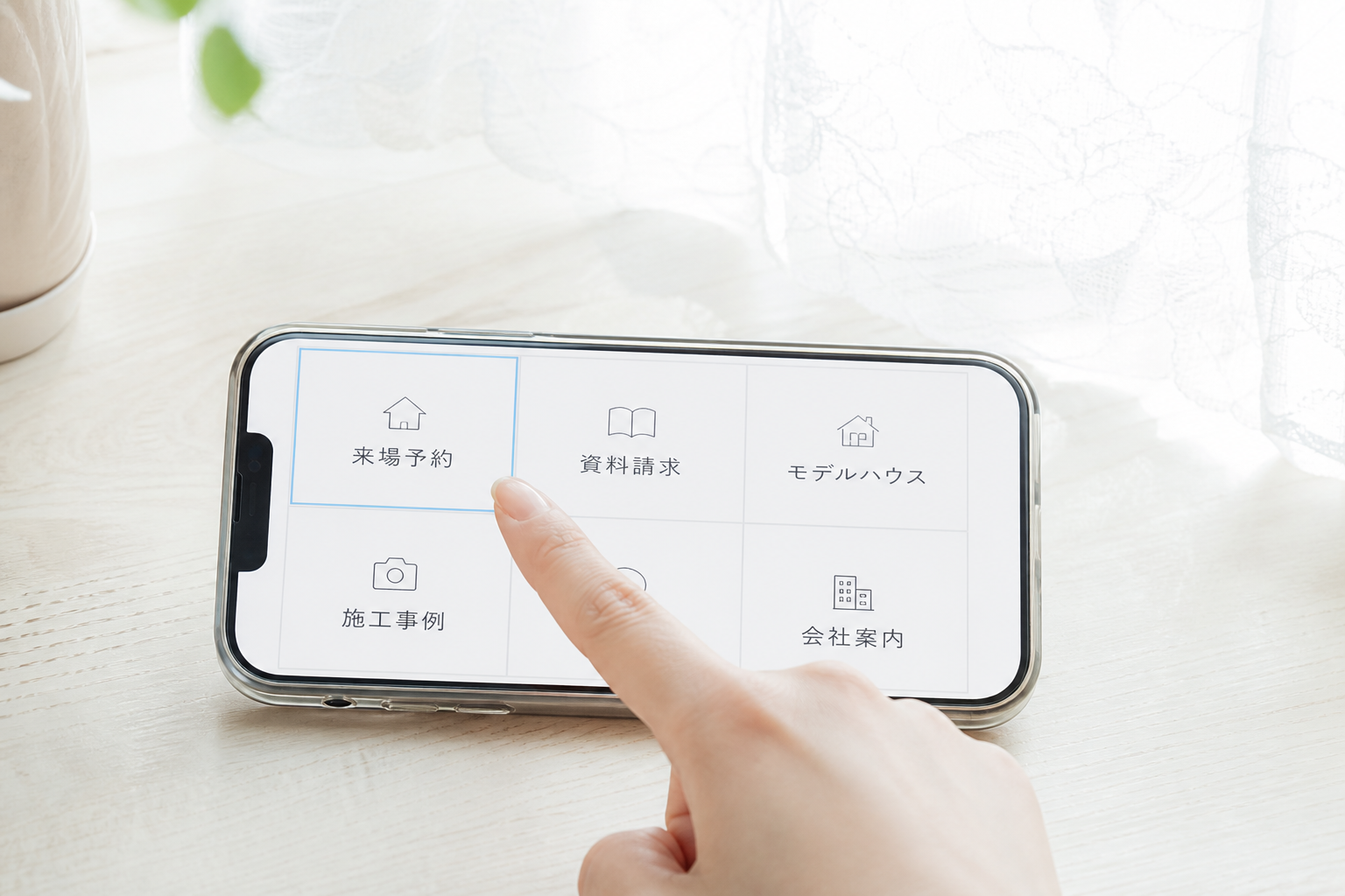 スマートフォンのリッチメニュー6分割画面のマクロ接写。左上「来場予約」のマスに女性の指がふれようとしている